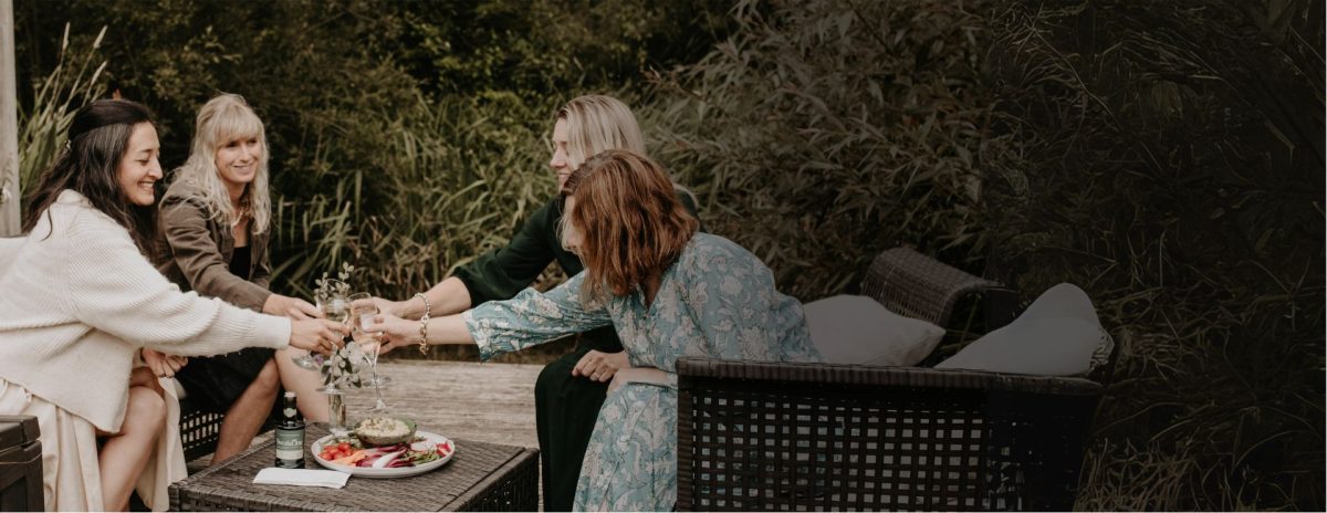 a group of women making a toast and enjoying two&One olive oil drizzle over humus. A club around olive oil